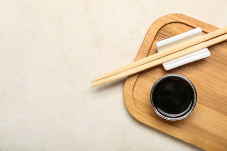 Bowl of soy sauce, chopsticks and wooden board on white backgroundの写真素材