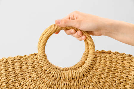 Woman holding rattan handbag on light background, closeupの写真素材
