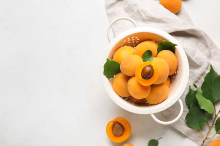 Colander full of ripe apricots on light backgroundの写真素材