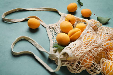 String shopping bag with ripe apricots on color background, closeupの写真素材