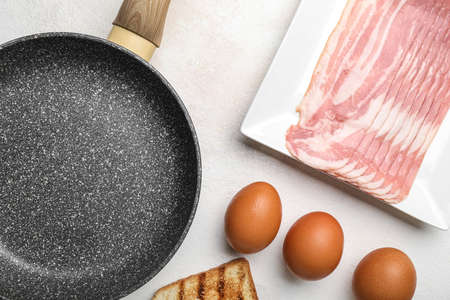 Frying pan, raw bacon and eggs on light background, closeupの写真素材