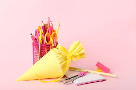 Cup with stationery and school cone on pink backgroundの写真素材