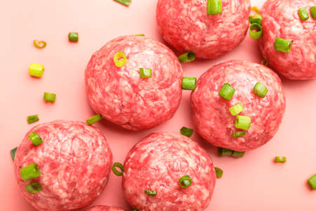 Raw meatballs with cut green onion on pink background, closeupの写真素材