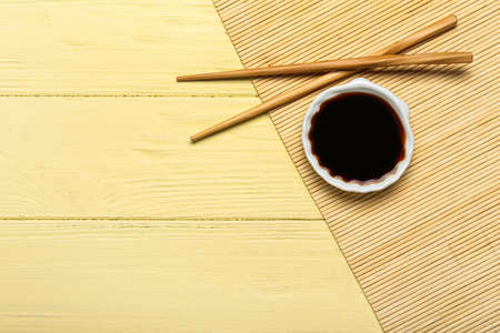 Bowl of soy sauce, chopsticks and bamboo mat on yellow wooden backgroundの写真素材