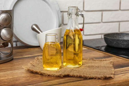Glass bottles of sunflower oil on table near white brick wall