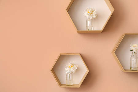 Shelves with beautiful peony flowers on beige wall