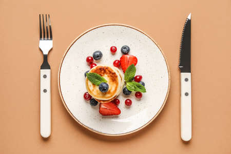 Plate with delicious cottage cheese pancakes and cutlery on color backgroundの写真素材