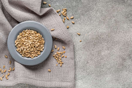 Bowl with peeled sunflower seeds and napkin on grunge backgroundの写真素材