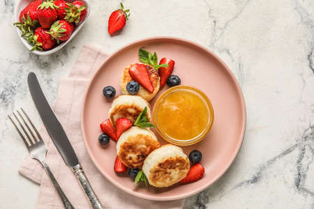 Plate with delicious cottage cheese pancakes, berries and honey served on light backgroundの写真素材