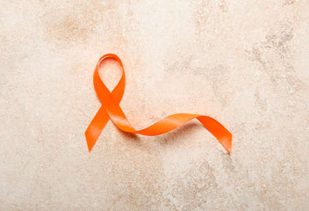 Orange awareness ribbon on grunge background. Kidney cancer concept