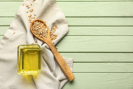 Bowl of oil, spoon with sunflower seeds and napkin on green wooden backgroundの写真素材