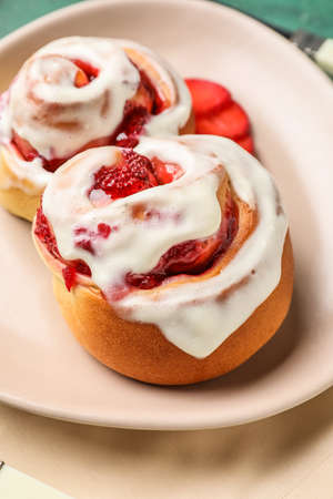 Plate with strawberry cinnamon rolls on green background, closeupの写真素材