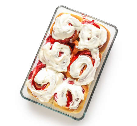 Baking dish with strawberry cinnamon rolls and cream on white backgroundの写真素材