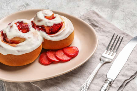 Plate with strawberry cinnamon rolls and cream on grunge background, closeupの写真素材