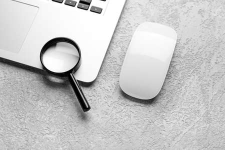 Laptop, mouse and magnifier on gray background. concept of searchの写真素材