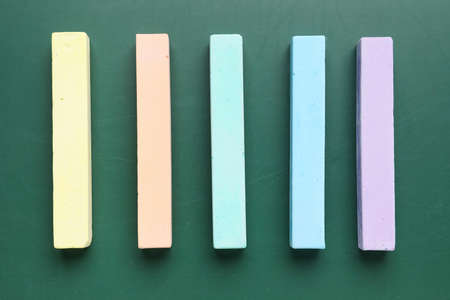 Colorful chalks on green blackboard, top view