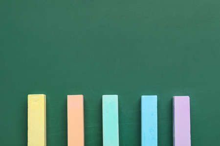 Colorful chalks on green blackboard, top view
