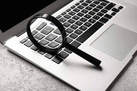 Laptop and magnifier on light background. concept of searchの写真素材
