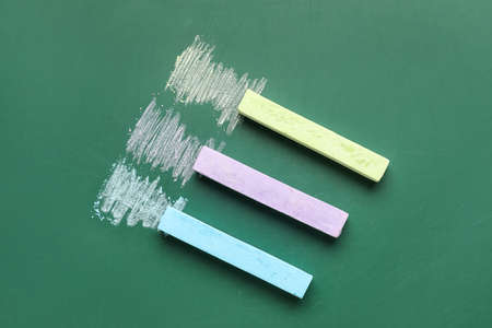 Colorful chalks on school blackboard, top view