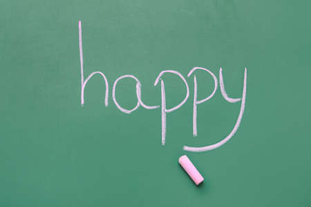 Word HAPPY with pink chalk on green blackboard