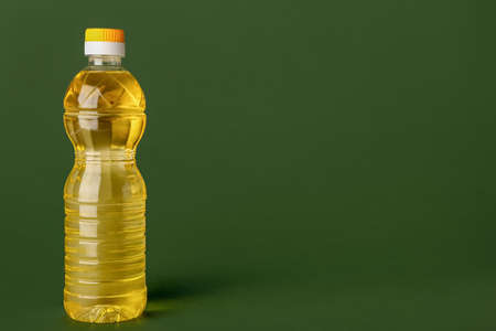 Bottle of sunflower oil on green background