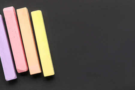 Pieces of colorful chalks on blackboard, top view