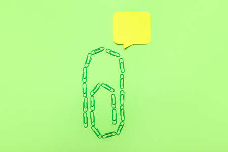 Paper clips with sticky note on green background