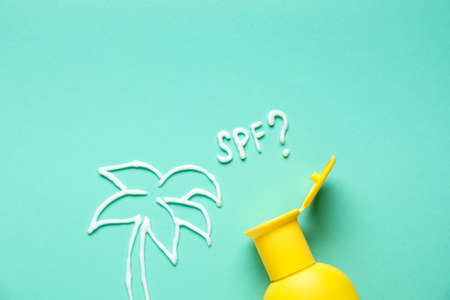 Drawing of palm tree and question SPF? made with sunscreen cream on color backgroundの写真素材