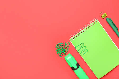 Green paper clips with stationery on red backgroundの写真素材