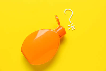 Bottle of sunscreen and question mark made of cream on yellow backgroundの写真素材