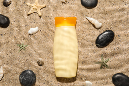 Sunscreen cream with starfishes, stones and seashells on sand