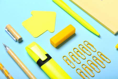 Yellow paper clips with stationery supplies on blue background