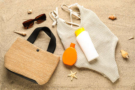 Bottles of sunscreen cream with beach accessories and seashells on sandの写真素材