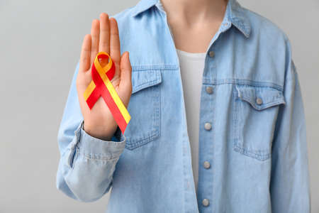 Woman with awareness ribbon on gray background, closeup. Hepatitis concept