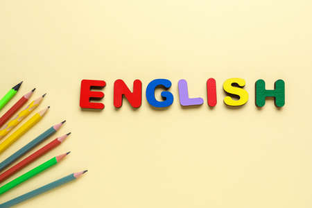 Word ENGLISH with pencils on beige background