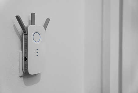 Modern wi-fi router hanging on light wall