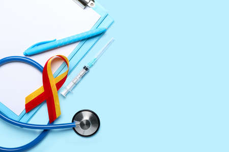 Awareness ribbon with stethoscope, syringe, pen and clipboard on blue background. Hepatitis conceptの写真素材