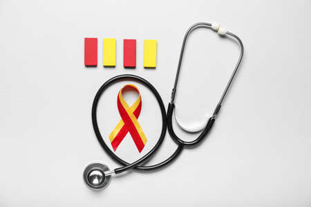 Awareness ribbon with blocks and stethoscope on light background. Hepatitis concept