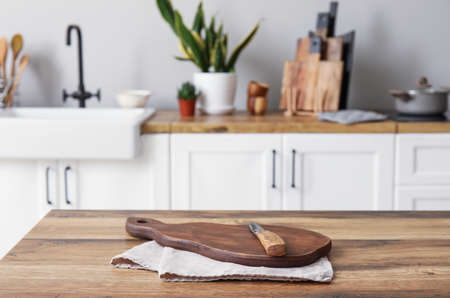 Cutting board with knife and napkin on table in light kitchen, closeup
