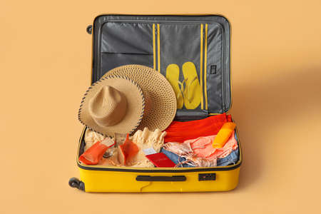 Open suitcase with clothes, passport and ticket on color backgroundの写真素材
