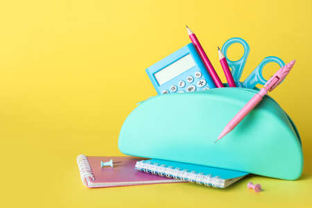 Blue pencil case with school stationery on blue background