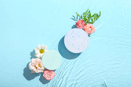 Beautiful composition with decorative stands and flowers in water against blue backgroundの写真素材