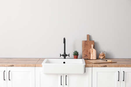 Cutting boards with jar of cookies, sink and houseplant on counters near light wall