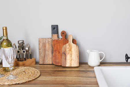 Cutting boards with kitchen utensils on counter near light wallの写真素材