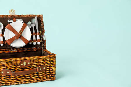 Wicker basket with tableware for picnic on blue backgroundの写真素材