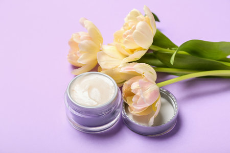 Bouquet of tulips and jar of facial cream on color backgroundの写真素材