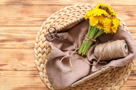 Basket with dandelions and rope on wooden backgroundの写真素材