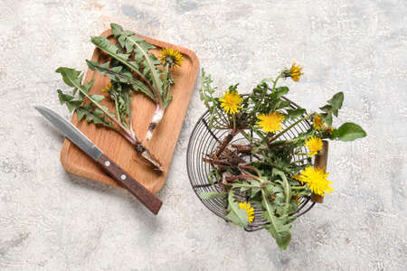 Yellow dandelions with basket, wooden board and knife on grunge backgroundの写真素材