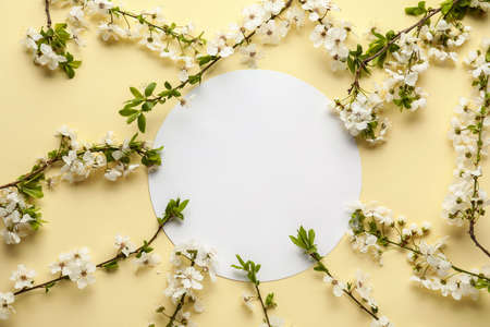 Beautiful blooming spring branches and blank card on light color background, top view