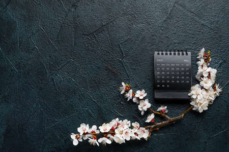 Beautiful blooming spring branches and calendar on dark background, top viewの写真素材